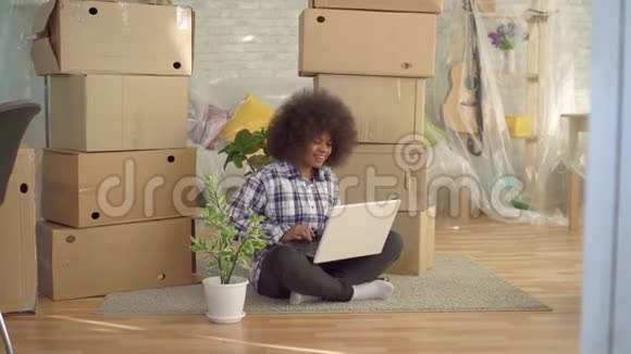 黑色女人有非洲发型坐在地板上使用笔记本电脑移动的概念视频的预览图