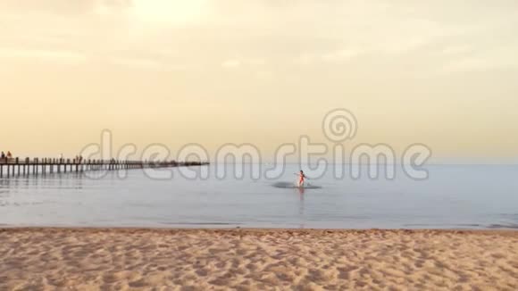 日落时分一个穿着泳衣的少女在海滩上的水中奔跑暑假在海上视频的预览图