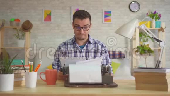 男作家在家里工作扔纸张热情地打字在一台旧打字机上视频的预览图