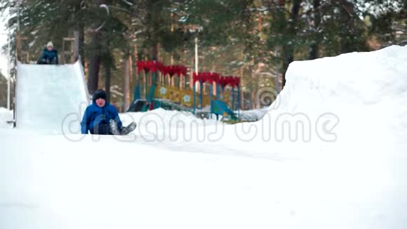 在冬季公园里男孩坐着雪橇和木制过山车视频的预览图