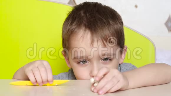 一个小的孩子用塑料模具把桌子上的一个人物靠近展现情感的男孩肖像快乐乐趣视频的预览图