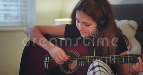 一位年轻女士在她的房间里弹吉他的肖像非常集中在镜头前笑得很可爱视频的预览图