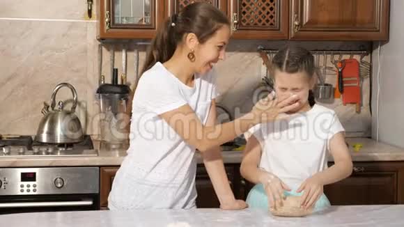 顽皮的妈妈和十几岁的女孩正在厨房里一起做饭互相涂粉视频的预览图