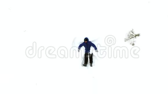 快乐的微笑男孩躺在雪地里移动他的手臂和腿做一个雪天使视频的预览图