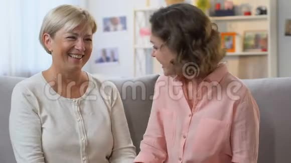 妈妈和女儿在沙发上笑分享好消息相信谈话视频的预览图