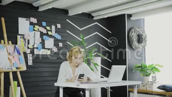 有魅力的商务女性看着手机然后在黑板上写东西视频的预览图