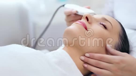 美容师中心超声削皮过程中的快乐女人脸特写视频的预览图