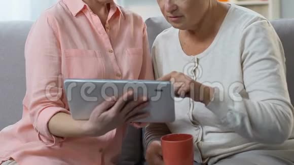 成年女儿教老妈用平板电脑显示视频通话应用视频的预览图