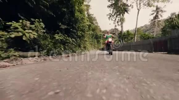 骑摩托车的人在棕榈树背景下的乡村道路上驾驶摩托车高级摩托车骑手视频的预览图