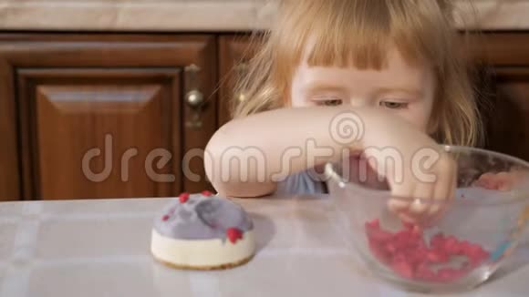 小可爱的女孩正在用覆盆子装饰小蛋糕视频的预览图