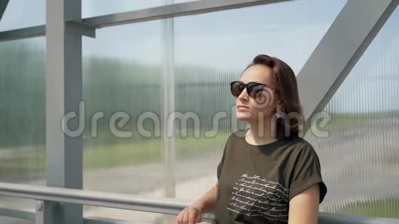 一个戴墨镜的女人站在桥上靠在栏杆上视频的预览图