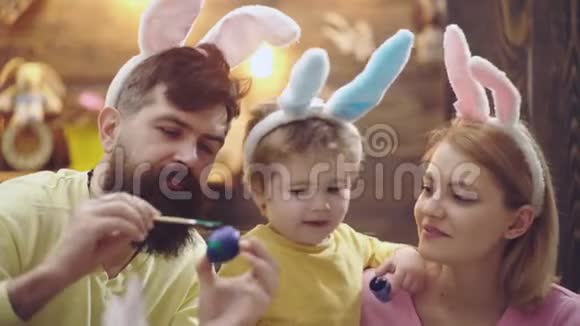 画复活节彩蛋的家庭的特写母亲父亲和他们的儿子画复活节彩蛋准备复活节视频的预览图
