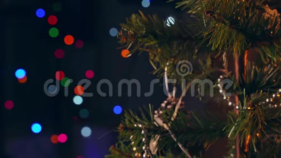 一个女孩正在圣诞树上挂着装饰圣诞的装饰品特写镜头在爸爸的发光二极管灯点亮视频的预览图