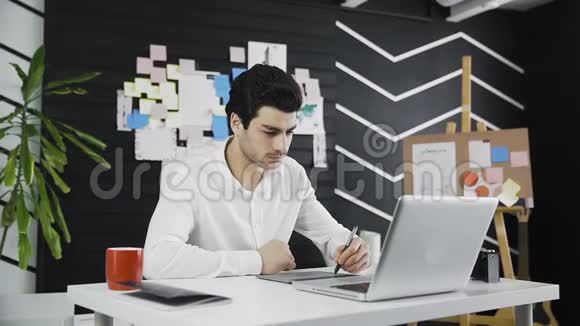 设计师在一间现代化的办公室里喝咖啡和使用平板电脑的多利镜头视频的预览图