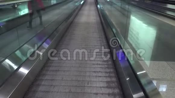 在机场的移动传送带上经过的人有人冲着飞机走在自动扶梯上视频的预览图