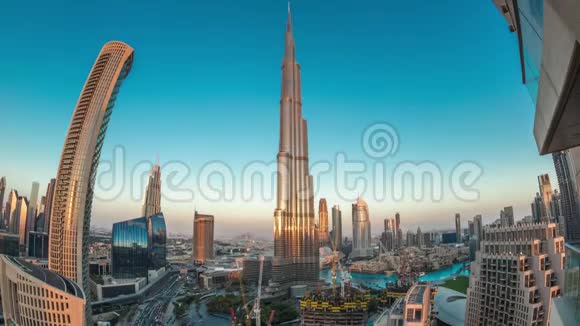 日落后迪拜市区的全景式天际线景观商场喷泉和摩天大楼在白天到夜间空中盘旋视频的预览图