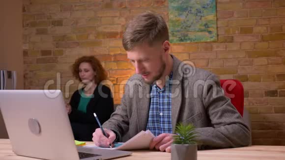 一个成年白种人商人在办公室里用笔记本电脑做特写镜头做生意的女商人视频的预览图