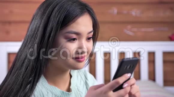 亚洲年轻女性用智能手机调情写信息的特写笑脸视频的预览图