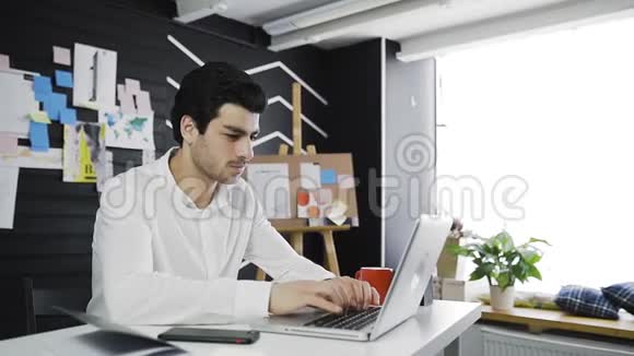 有胡子的商人在阁楼办公室的笔记本电脑键盘上打字视频的预览图