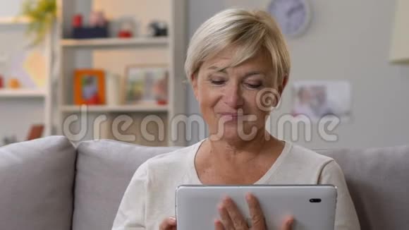奶奶在平板电脑上查看节日应用程序和孙女一起庆祝生日视频的预览图