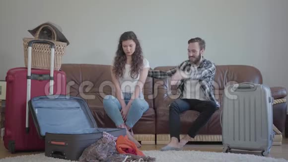 坐在沙发上靠在沙发上的时候一个穿格子衬衫的蓄着胡子的年轻人和一个黑发的女孩在争吵视频的预览图