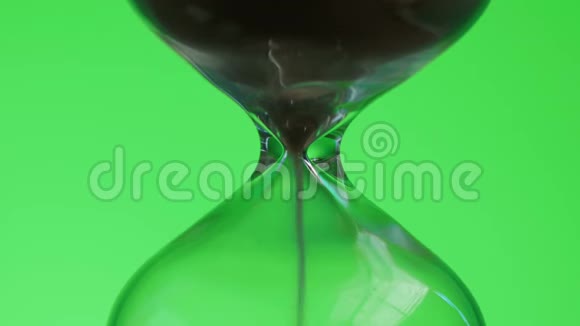 绿色背景上的玻璃沙子正从一个部分倾泻到另一个部分时间和瞬变概念视频的预览图