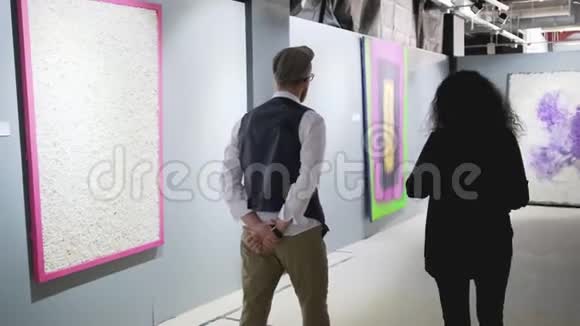 男人和女人在艺术画廊的大厅里走动谈论图片视频的预览图