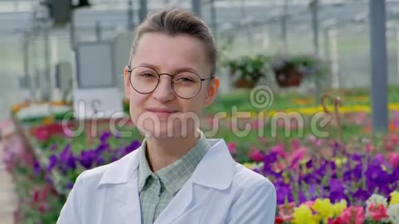 年轻漂亮的中年妇女戴着眼镜穿着白色外套戴着蓝色橡胶手套一位科学家农学家摆着姿势视频的预览图