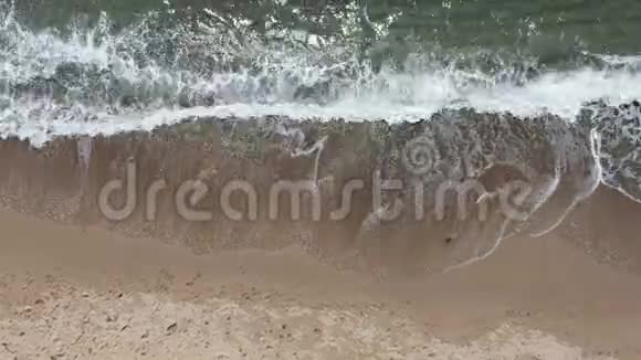 空气带泡沫的海浪正试图上岸冲走人们在沙滩上留下的痕迹视频的预览图