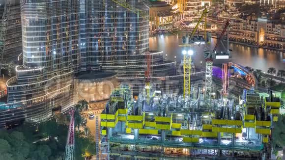在迪拜一座正在建造的摩天大楼的空中景观与巨大的起重机夜间时间间隔视频的预览图