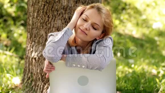 梦中的女孩在公园里休息有笔记本电脑的梦中女人在户外工作为梦想准备一分钟技术和互联网视频的预览图