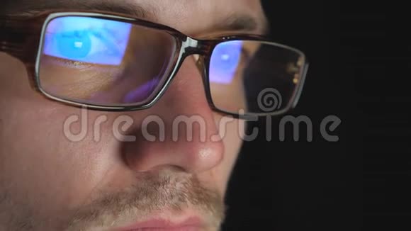 戴眼镜的企业家的男性眼睛看着笔记本电脑屏幕深夜工作年轻的商人视频的预览图