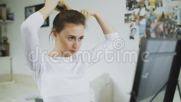 女人看着镜子把她光滑的长发扎成马尾辫做发型视频的预览图
