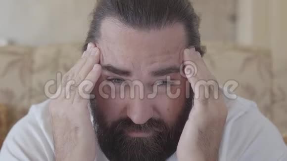 特写一个留胡子的人的肖像他头痛用手揉着他的头视频的预览图