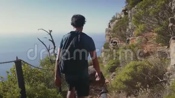 徒步旅行者在海边悬崖上行走的后景视频的预览图