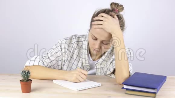 女孩在笔记本上写字疲劳地揉着脸视频的预览图