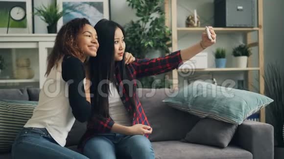 漂亮的年轻女士正在家里用智能手机自拍看着屏幕微笑着摆姿势拍照青年视频的预览图