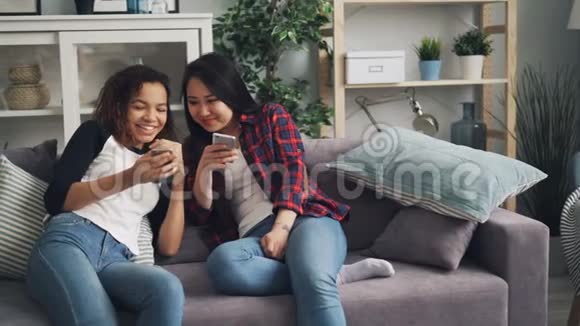 活泼开朗的亚裔和非裔美国人会谈笑风生地看着智能手机屏幕上的小玩意视频的预览图