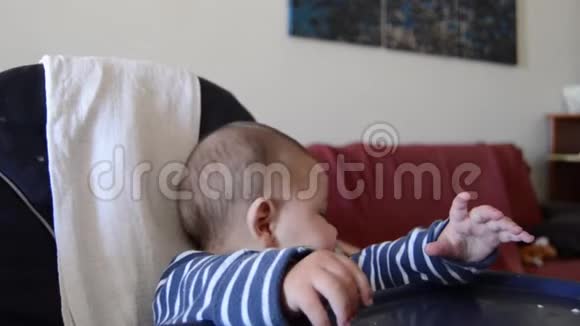 饥饿的婴儿没有耐心等待食物妈妈在高椅上喂六个月大的小男孩视频的预览图