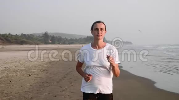 受伤膝盖上有绷带的女人正在沙滩上奔跑视频的预览图
