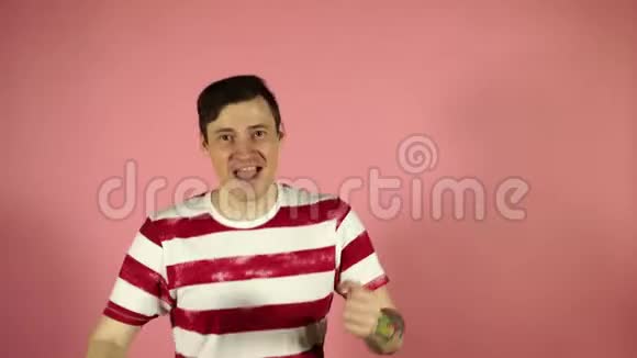 穿着纹身跳舞看着粉色背景镜头的快乐男人视频的预览图