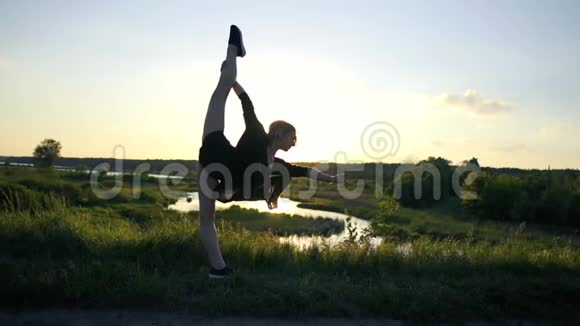 春天的女孩弯着腰做着一个前面的劈裂就像一个风帆在一个湖在斯洛文尼亚视频的预览图