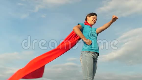 女孩梦想成为超级英雄对抗蓝天站在红色斗篷里的年轻女孩表达了梦想美丽美丽视频的预览图