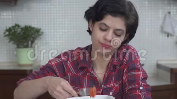 年轻女孩剪短头发吃着美味的新鲜沙拉配上番茄和蔬菜尽情享受视频的预览图