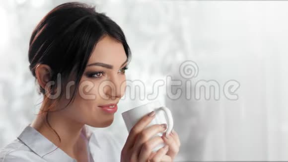 中等特写快乐愉快的年轻女人喝咖啡或茶拿着白色杯子视频的预览图