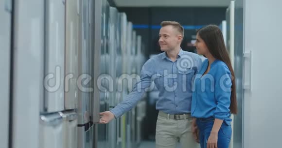 一对年轻的夫妇打开新冰箱的门在消费者购买前先检查一下冰箱的设计和质量视频的预览图