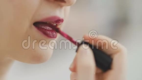 年轻女子涂着时髦的伴侣口红对着镜子检查自己化妆诱惑吸引视频的预览图