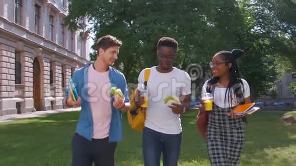 三个年轻的多民族饥饿的学生在户外站立时讨论吃午饭和吃食物视频的预览图