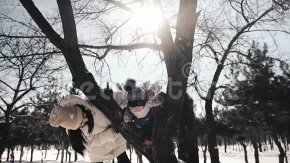 一个34岁的小男孩爬上树枝妈妈鼓励他和树篱然后亲吻欣赏力量视频的预览图