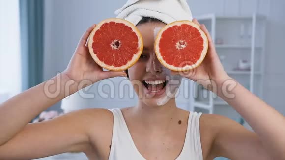 肖像照片英俊的年轻女子摆姿势两个半葡萄柚在眼睛上面具在半脸视频的预览图